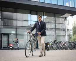 曼schiebt盛Fahrrad uber窝坐伏尔einem Burogebaude。